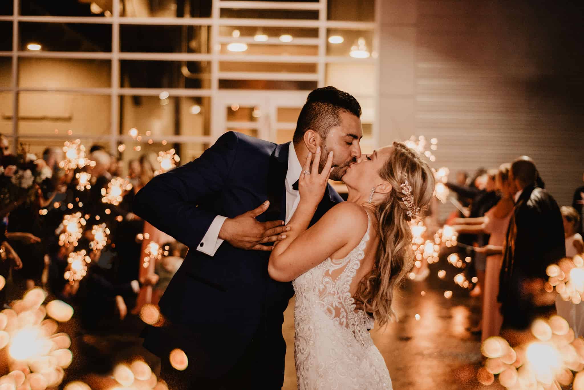 Romantic wedding couple sharing a kiss at SKY Armory with sparklers in the background.