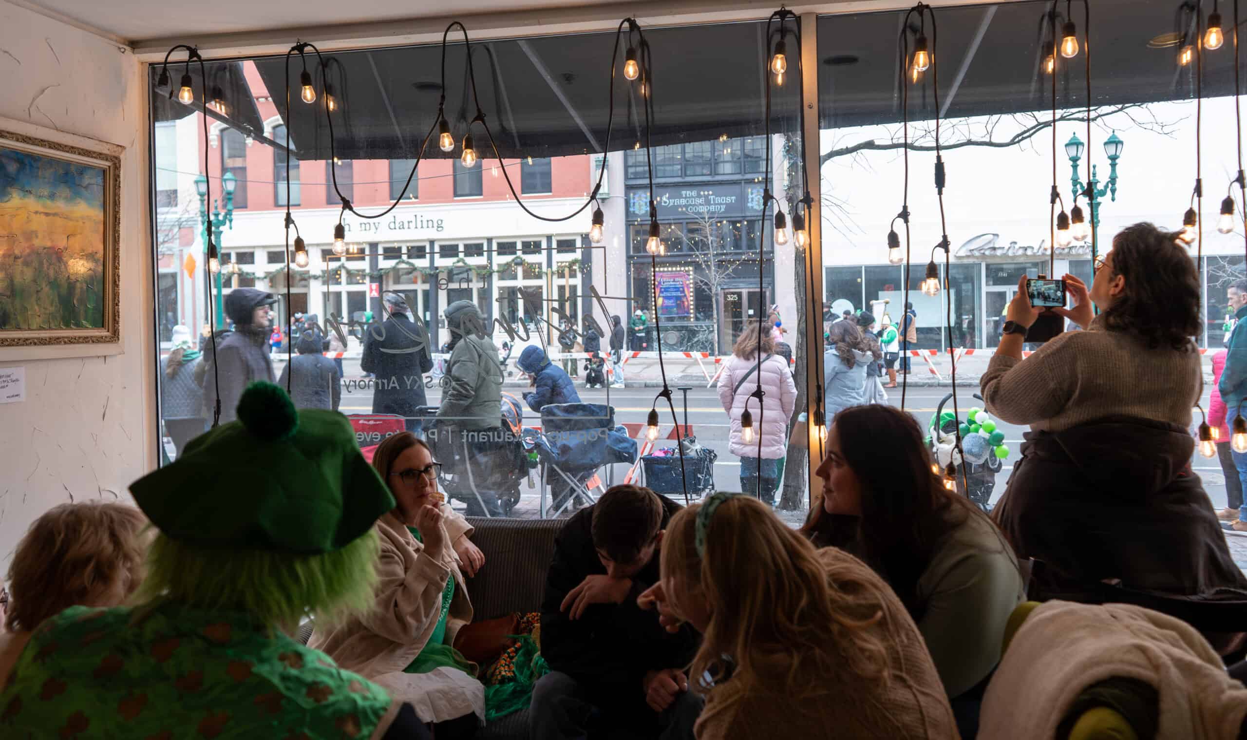 People enjoying indoor seating at Sky Armory with large window view.