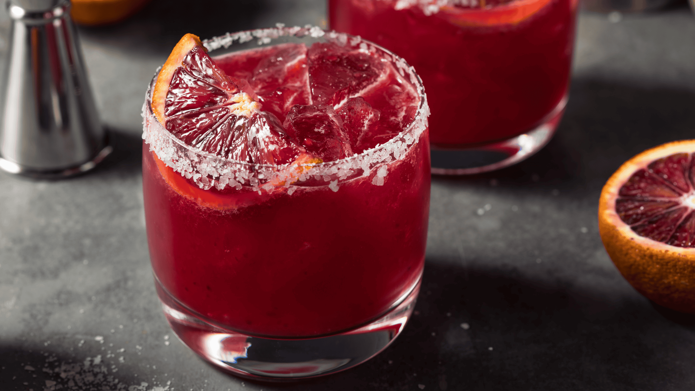 Refreshing red blood orange cocktail with salt rim and citrus garnish.