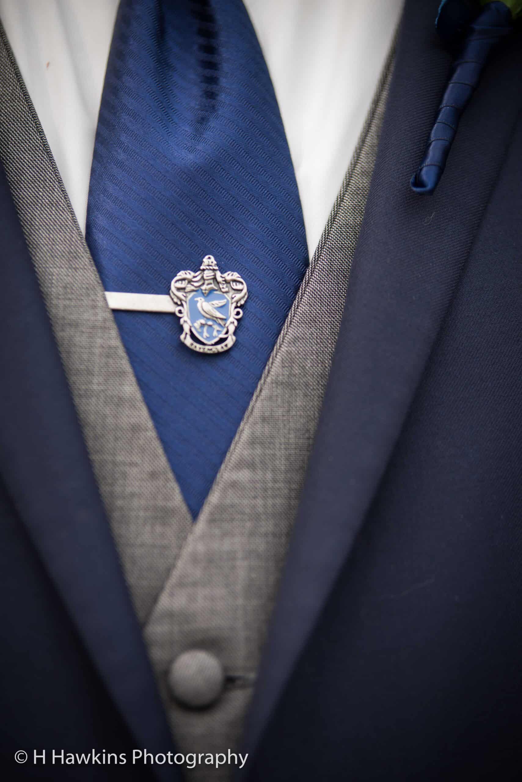 Close-up of a tailored suit with SKY Armory lapel pin and blue tie.