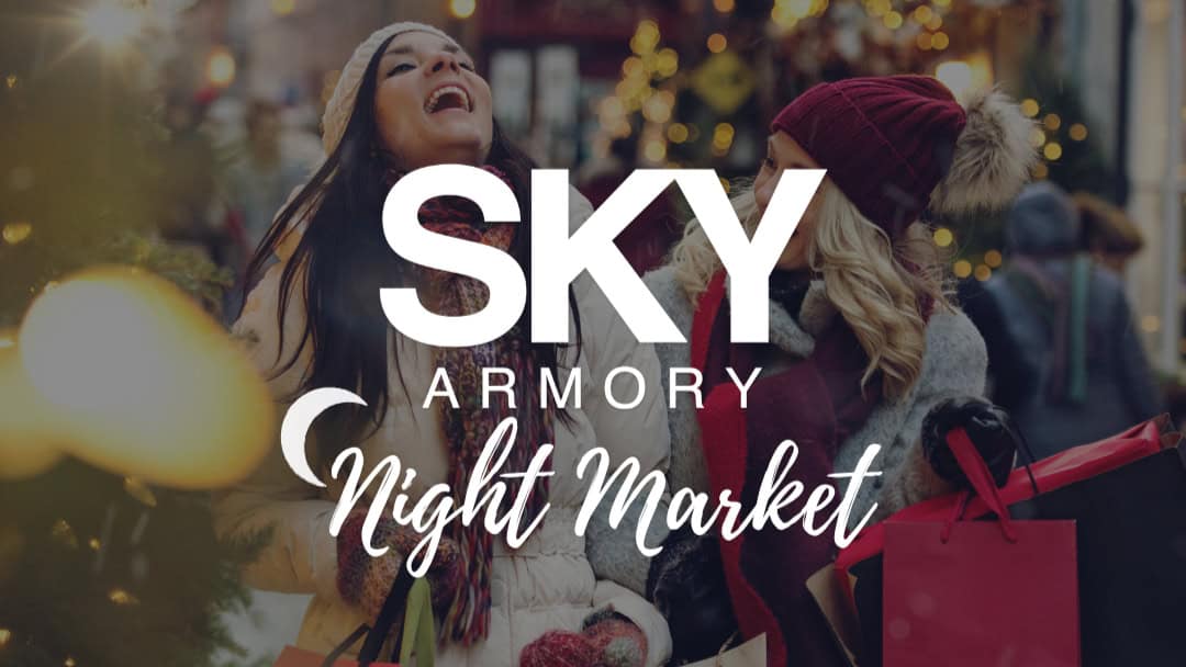 People enjoying SKY Armory Night Market with festive lights and shopping.