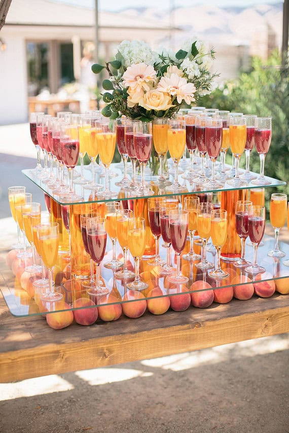 Colorful summer wedding drink display with floral centerpiece.