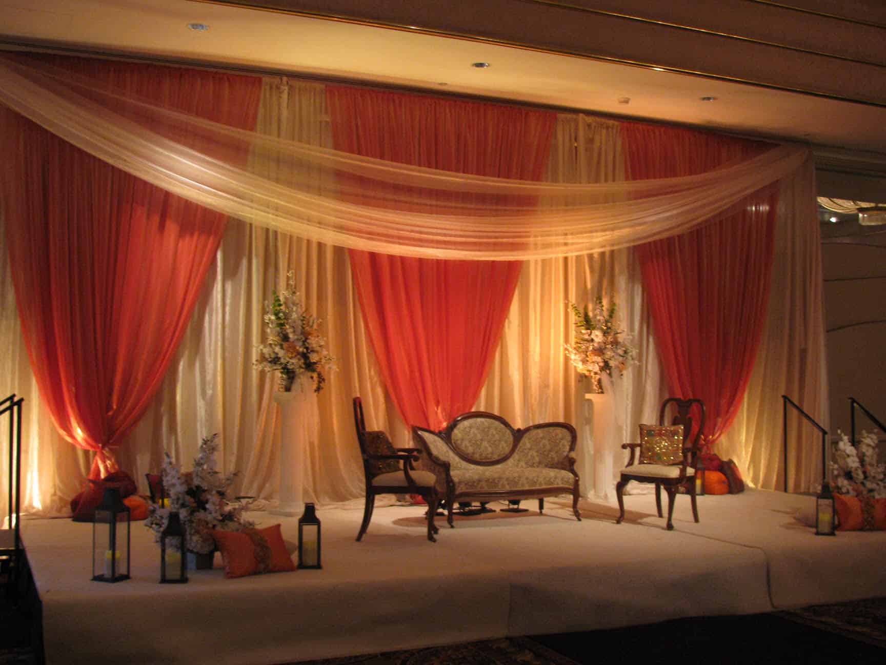 Beautiful wedding stage with draped curtains and floral arrangements.