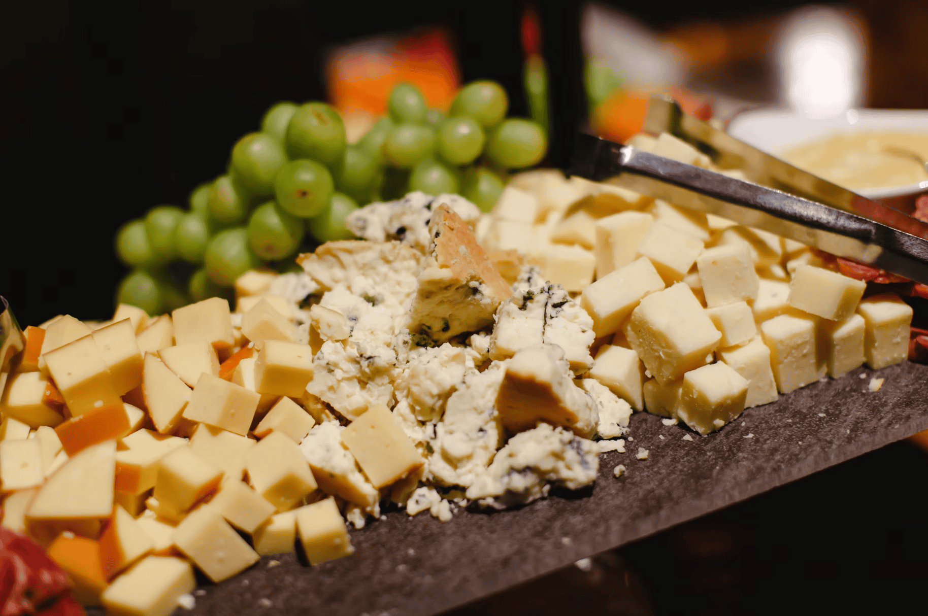 Cheese and green grapes on a cheese platter with cheese cubes and cheese spread.