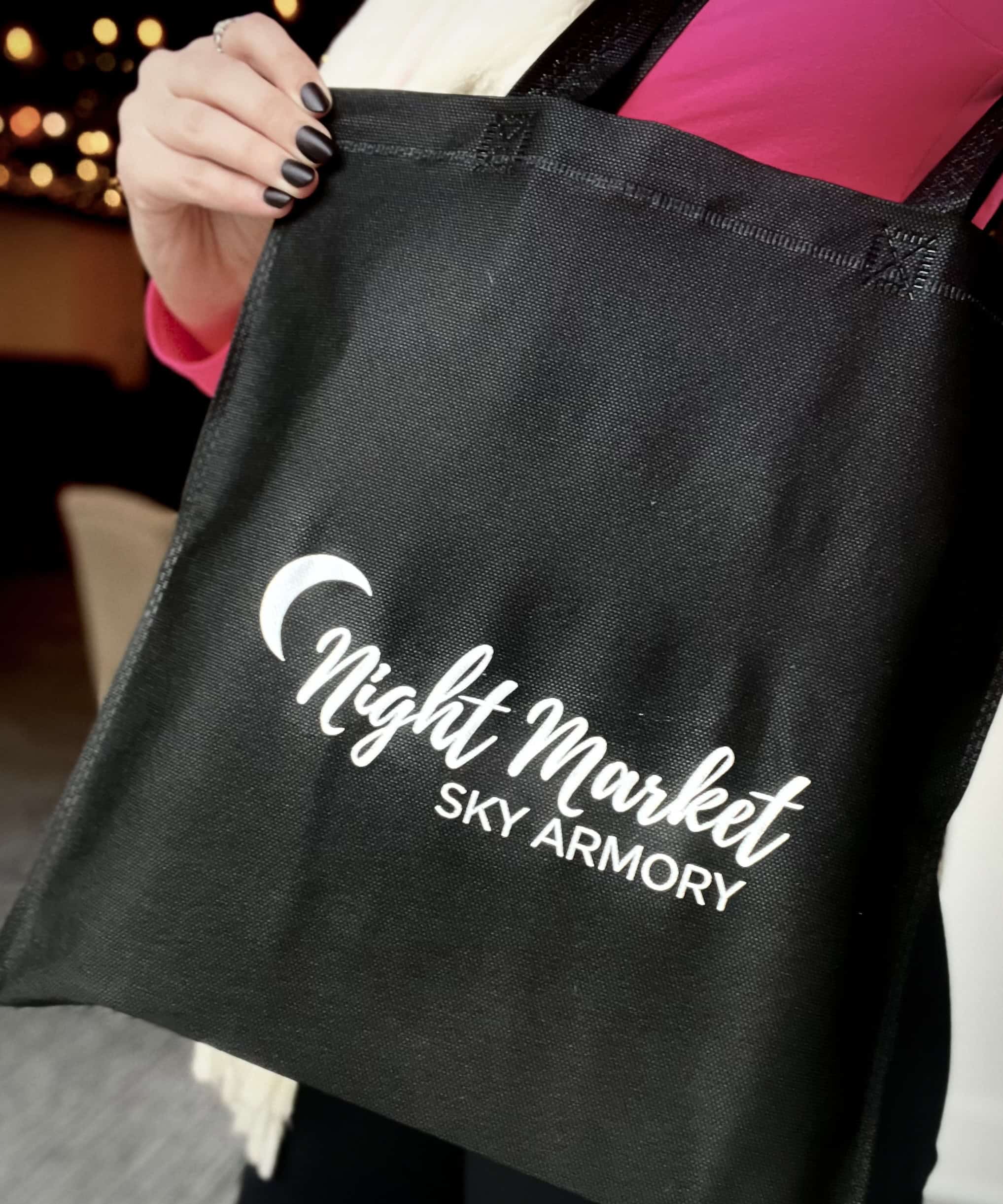 Black tote bag with Night Market SKY Armory logo for event promotion.