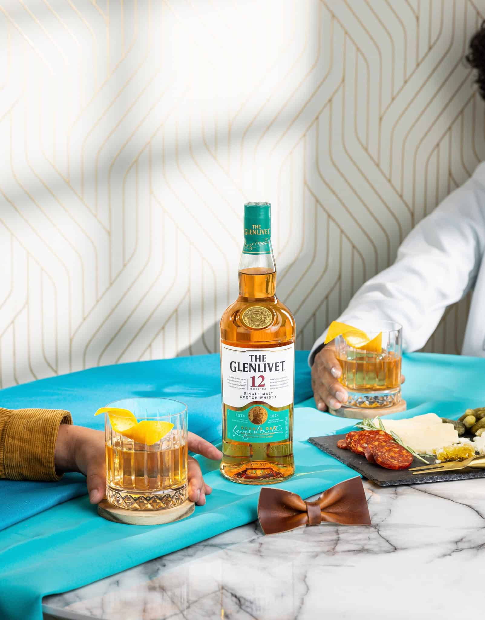 Two whiskey glasses with lemon slices and a bottle of The Glenlivet 12.