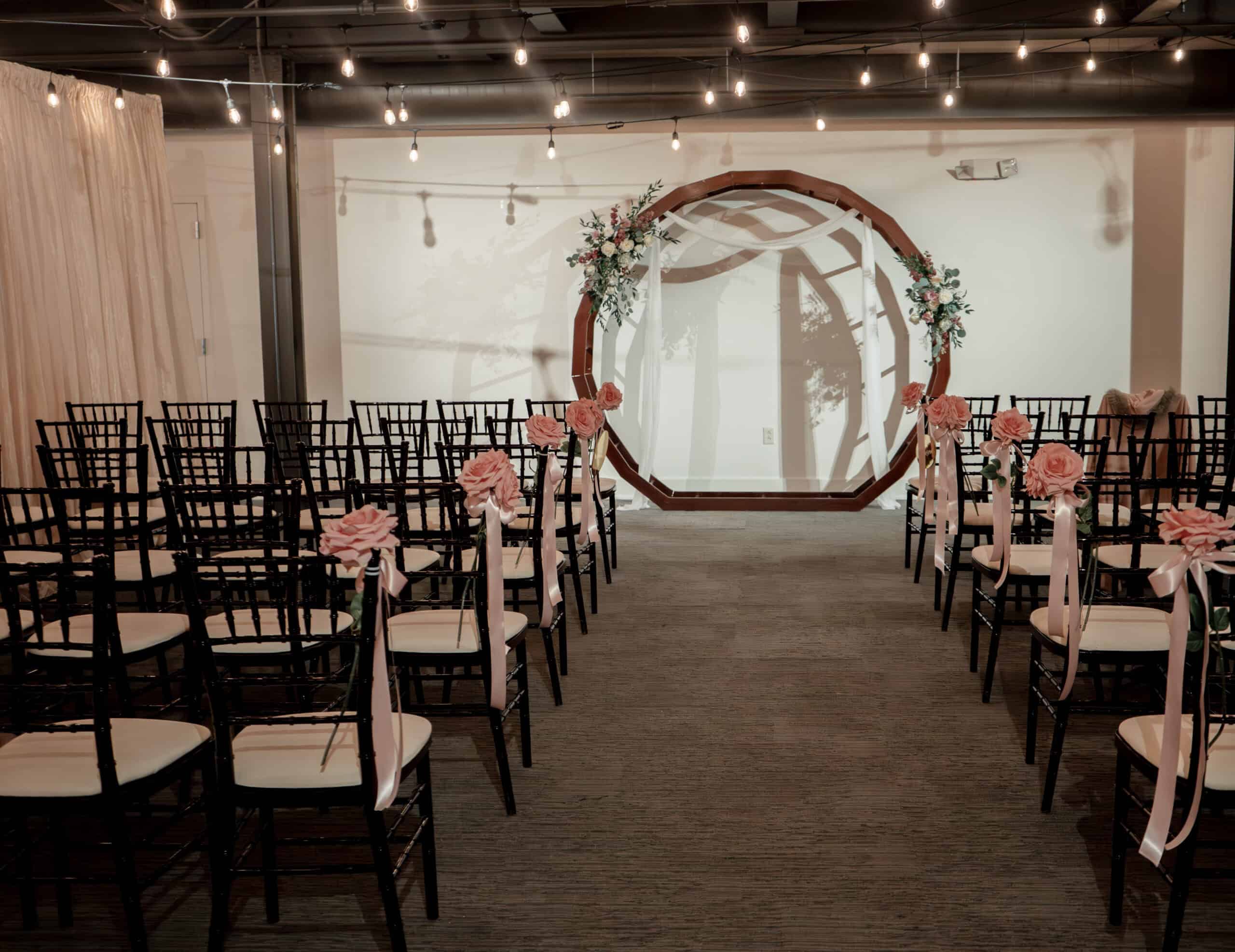 Wedding ceremony setup with chairs, floral decorations, and a circular arch at SKY Armory.
