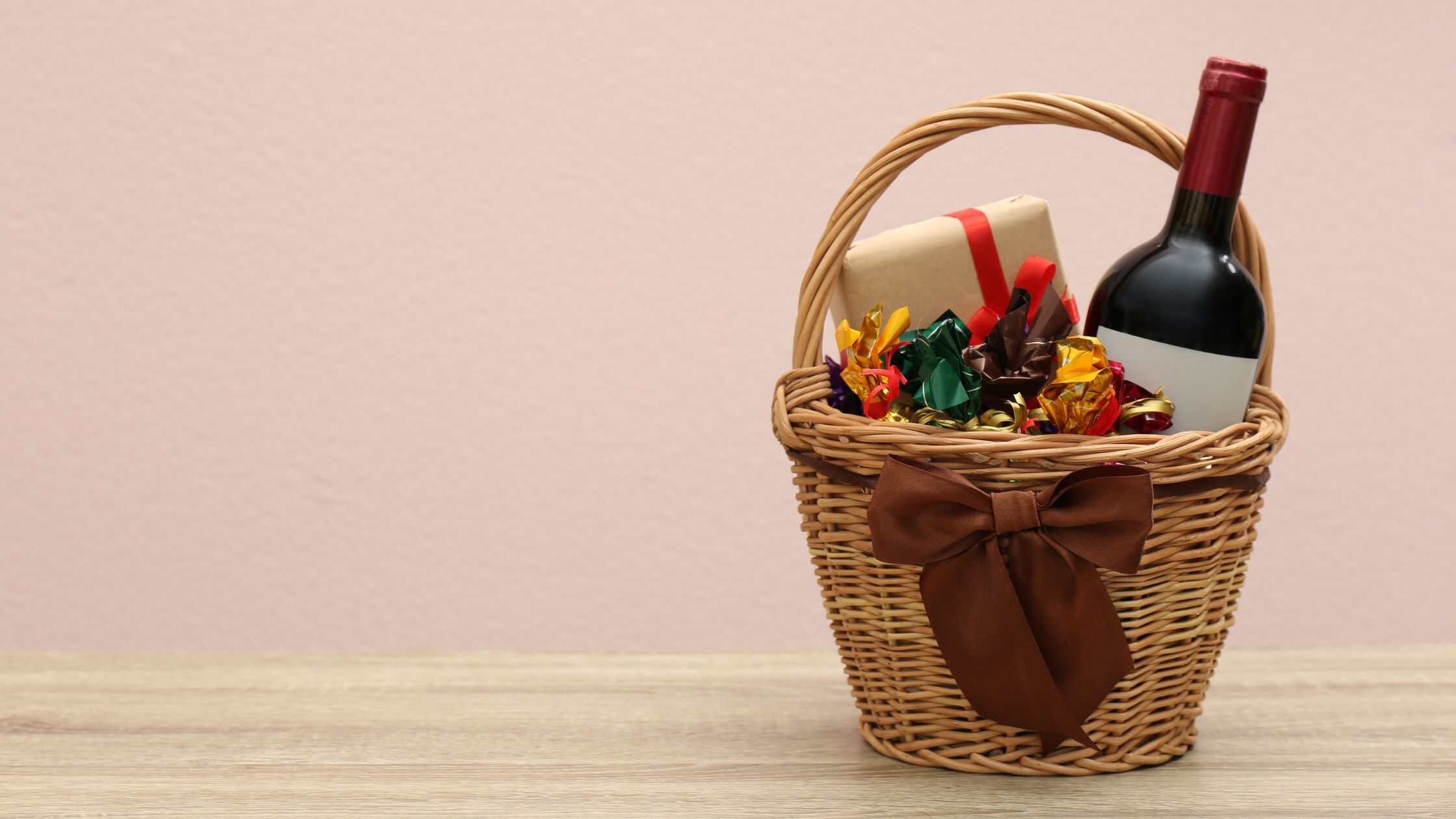 Wicker gift basket with wine, chocolates, and festive decorations.
