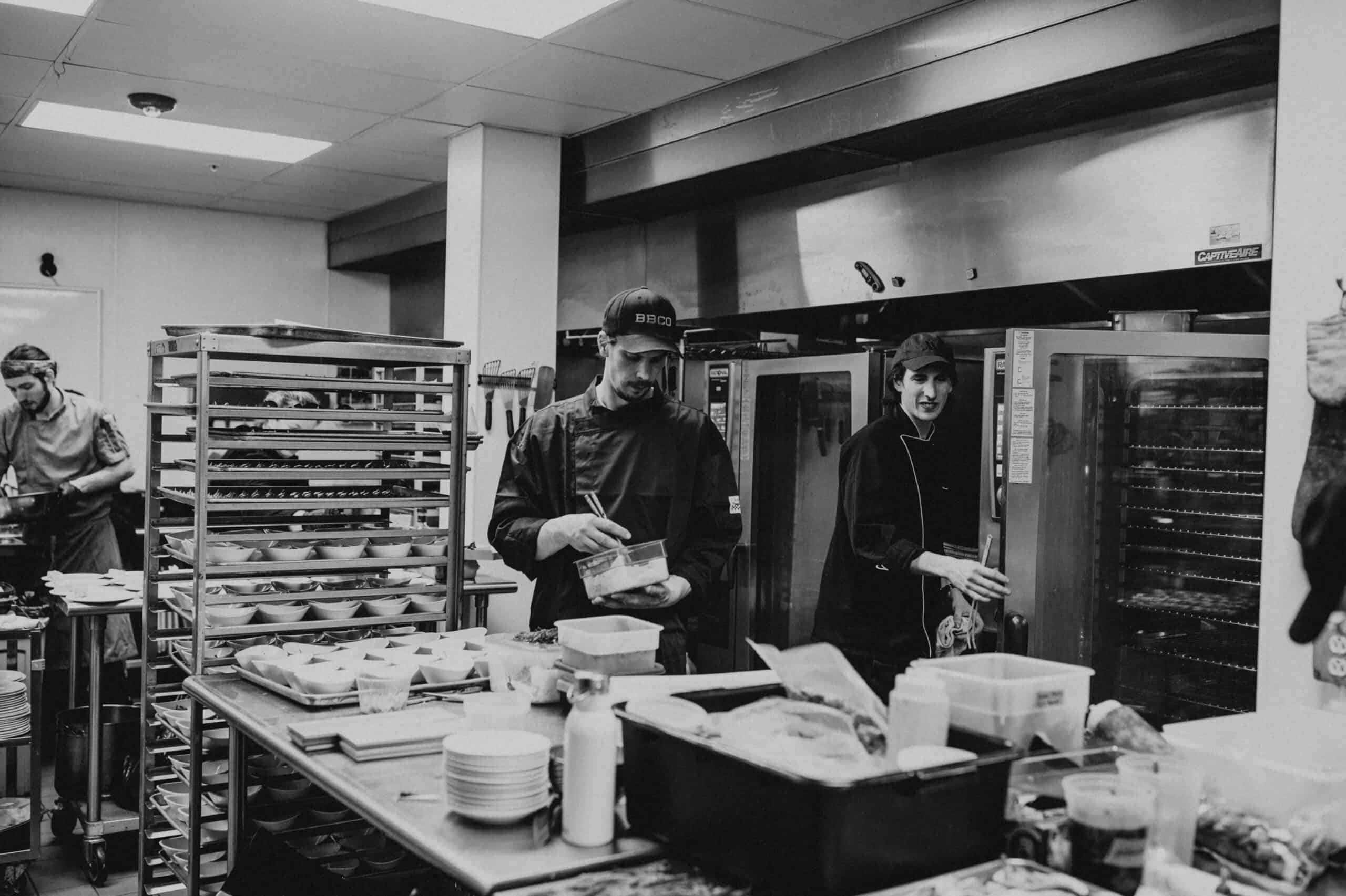 Kitchen staff preparing food in a professional kitchen environment.