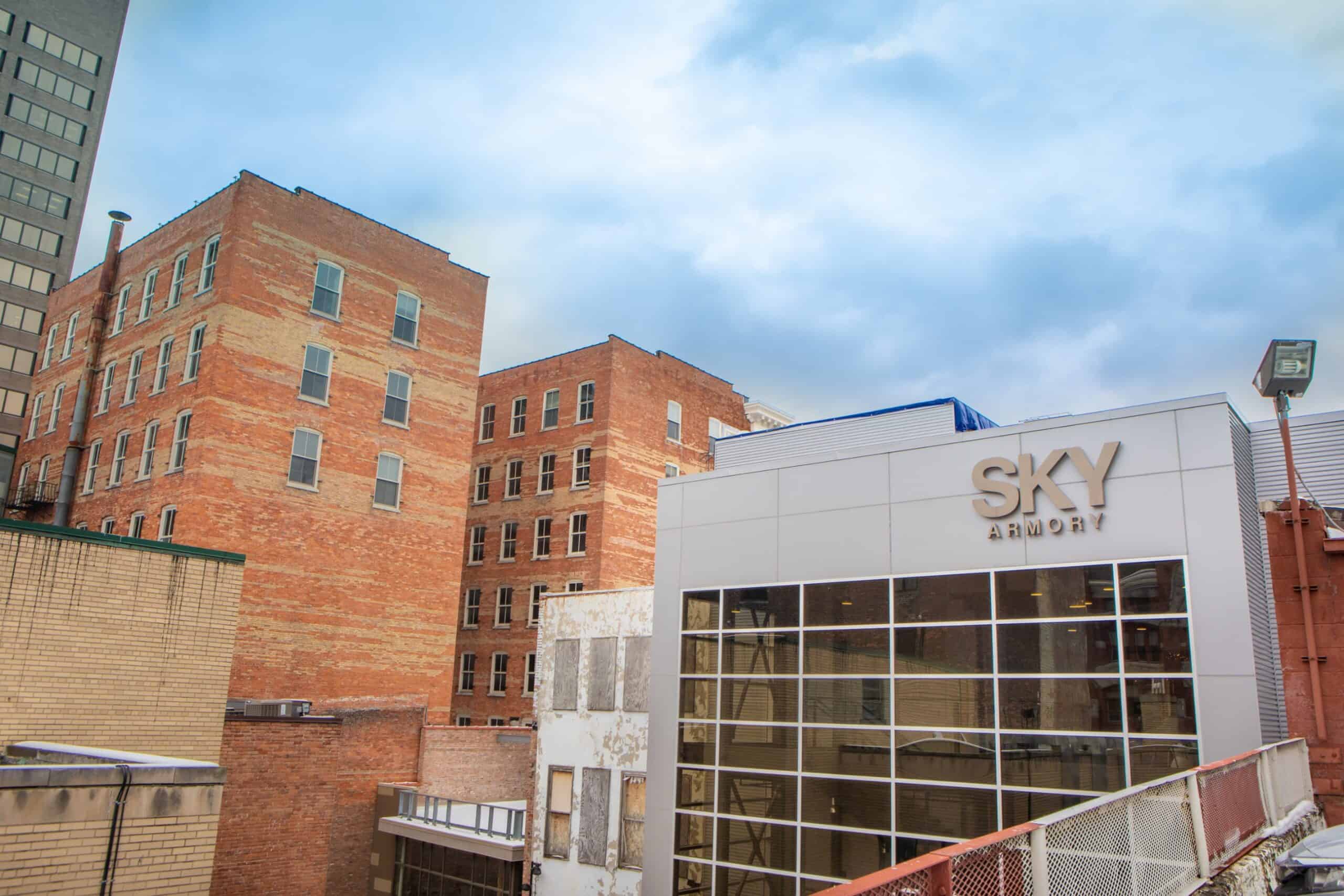 Exterior view of SKY Armory with brick buildings and modern glass facade.