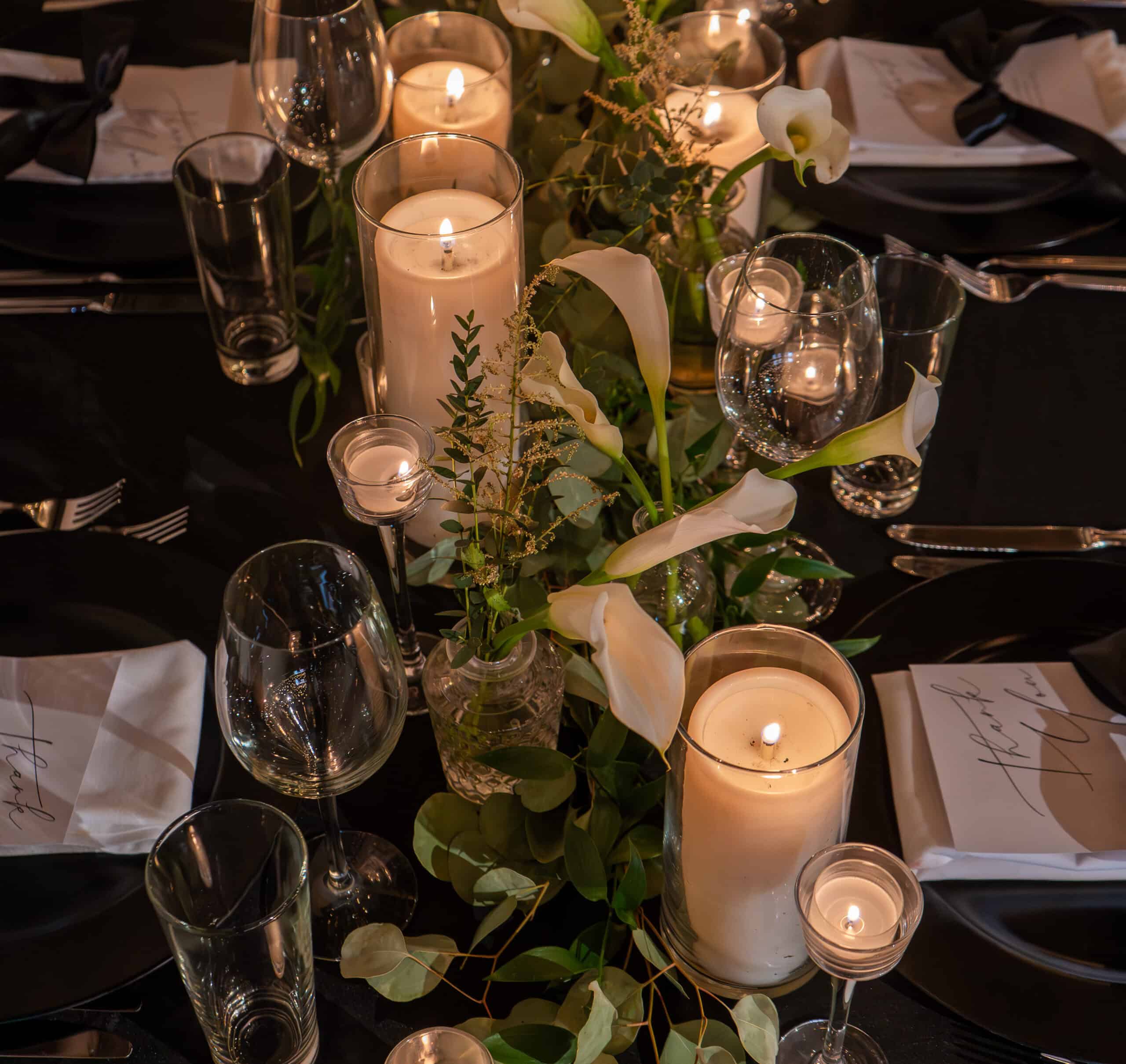 Elegant table setting with candles, flowers, and glassware for a formal event.