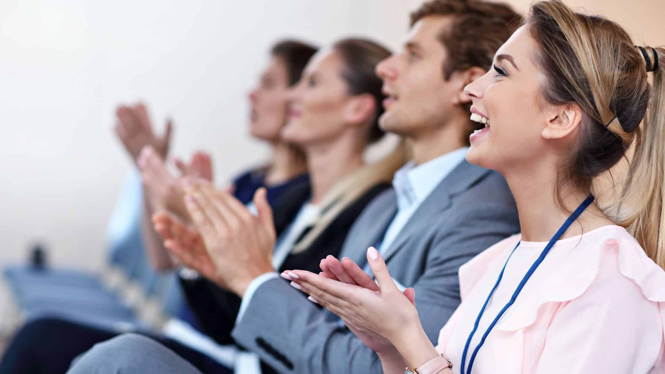 Happy employees clapping and engaging during a team meeting or presentation.