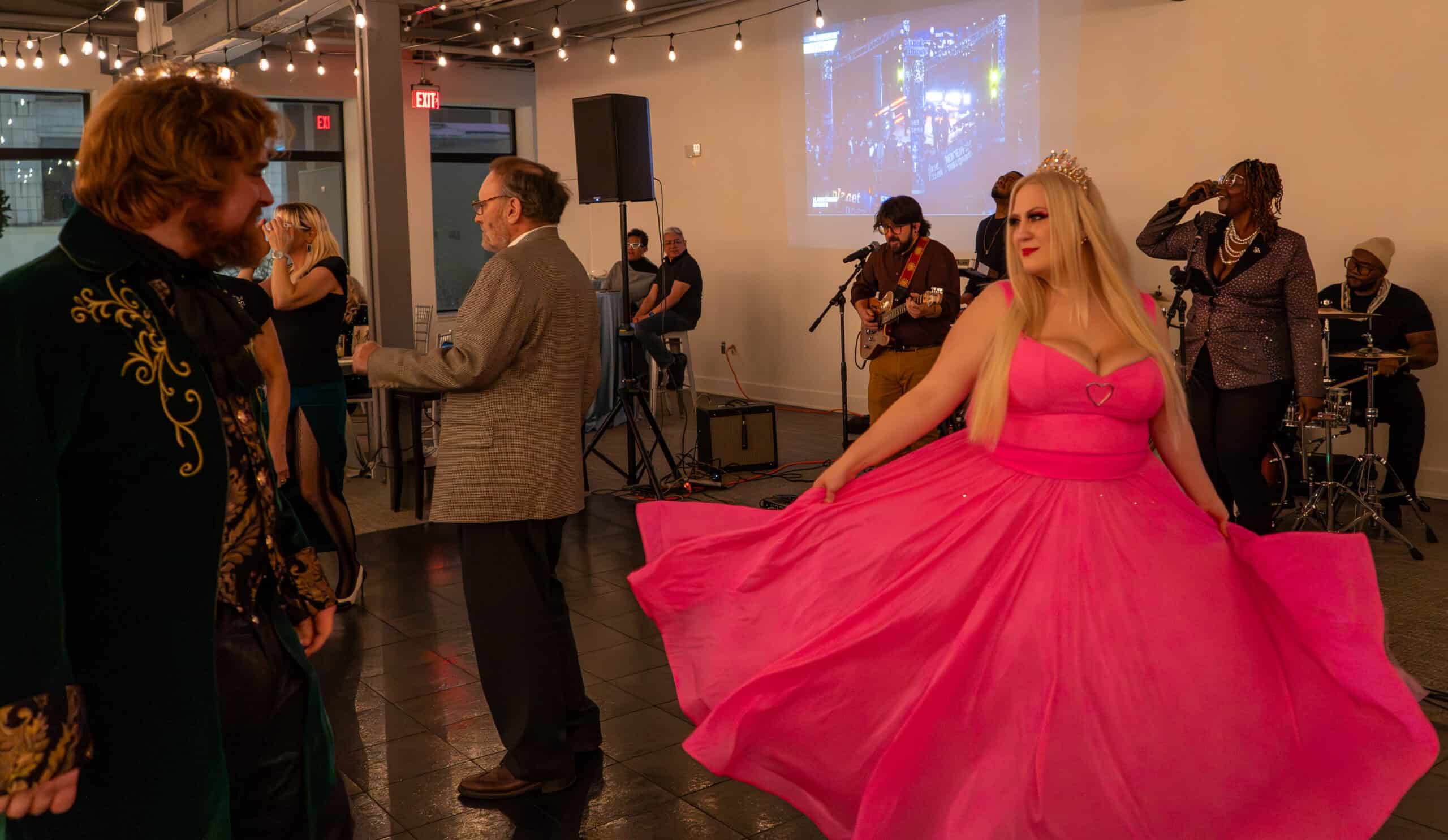 Woman in pink dress dancing at SKY Armory event with live band and guests.