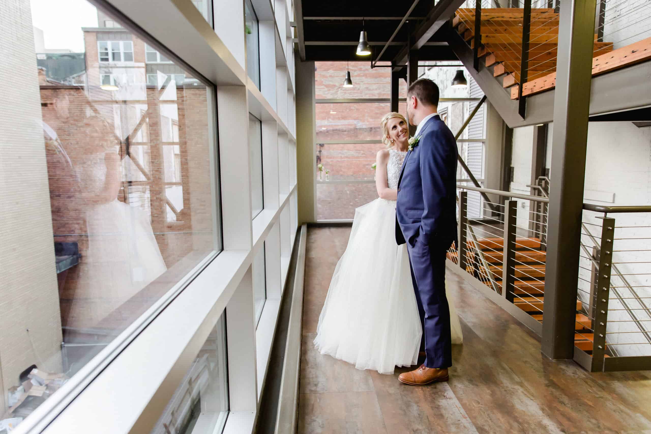 Bride and groom in wedding attire at SKY Armory, NYC, with modern industrial interior.
