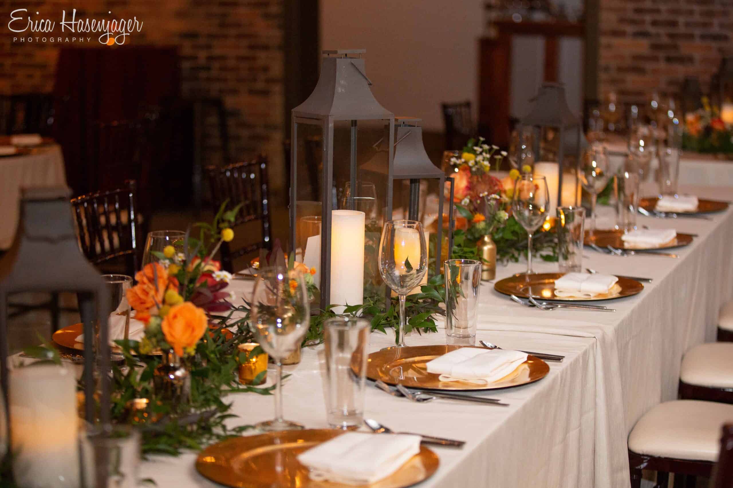 Decorated wedding reception table with candles, flowers, and elegant tableware.