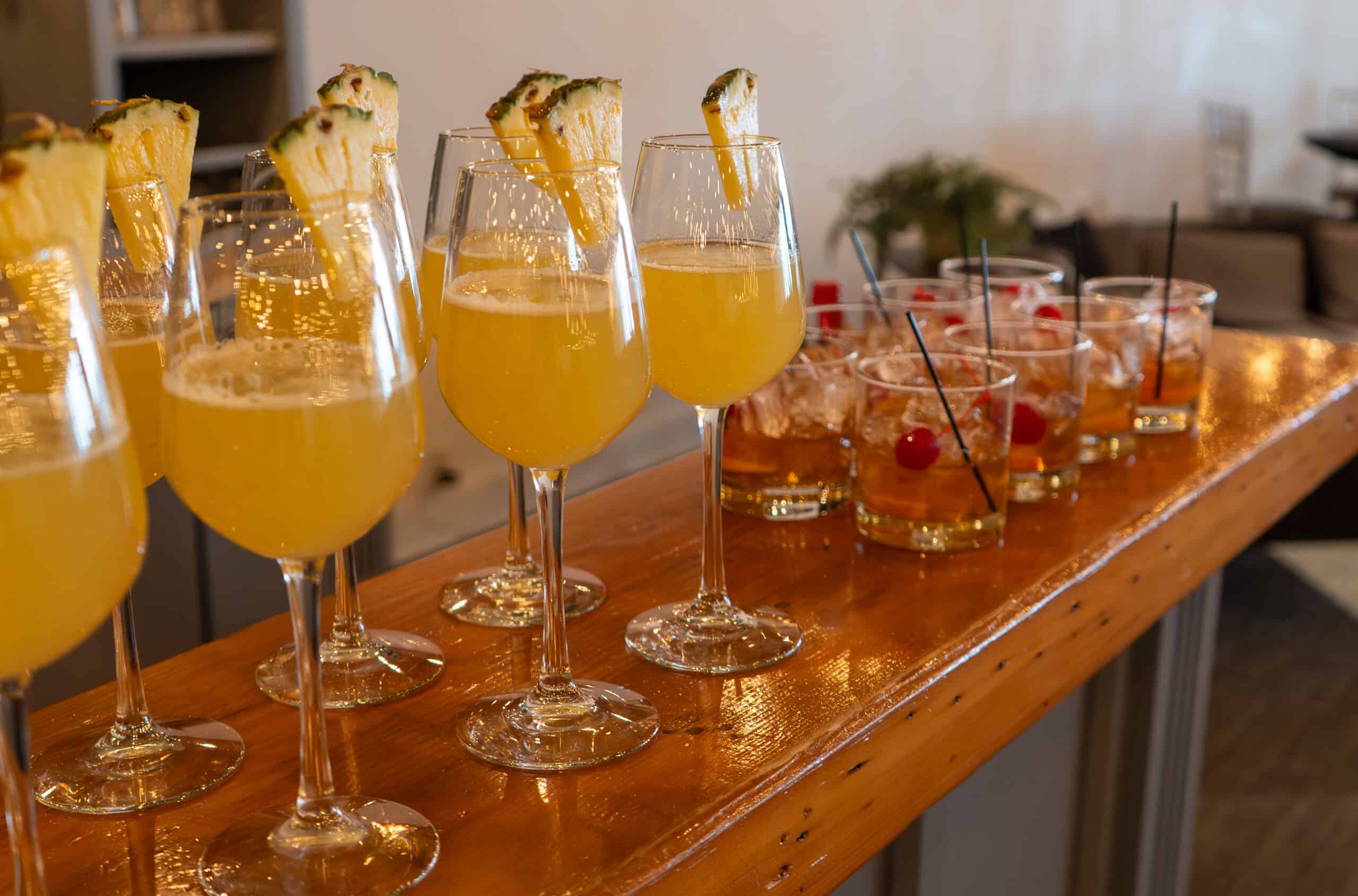 Assorted cocktails with garnishes on a wooden bar counter.