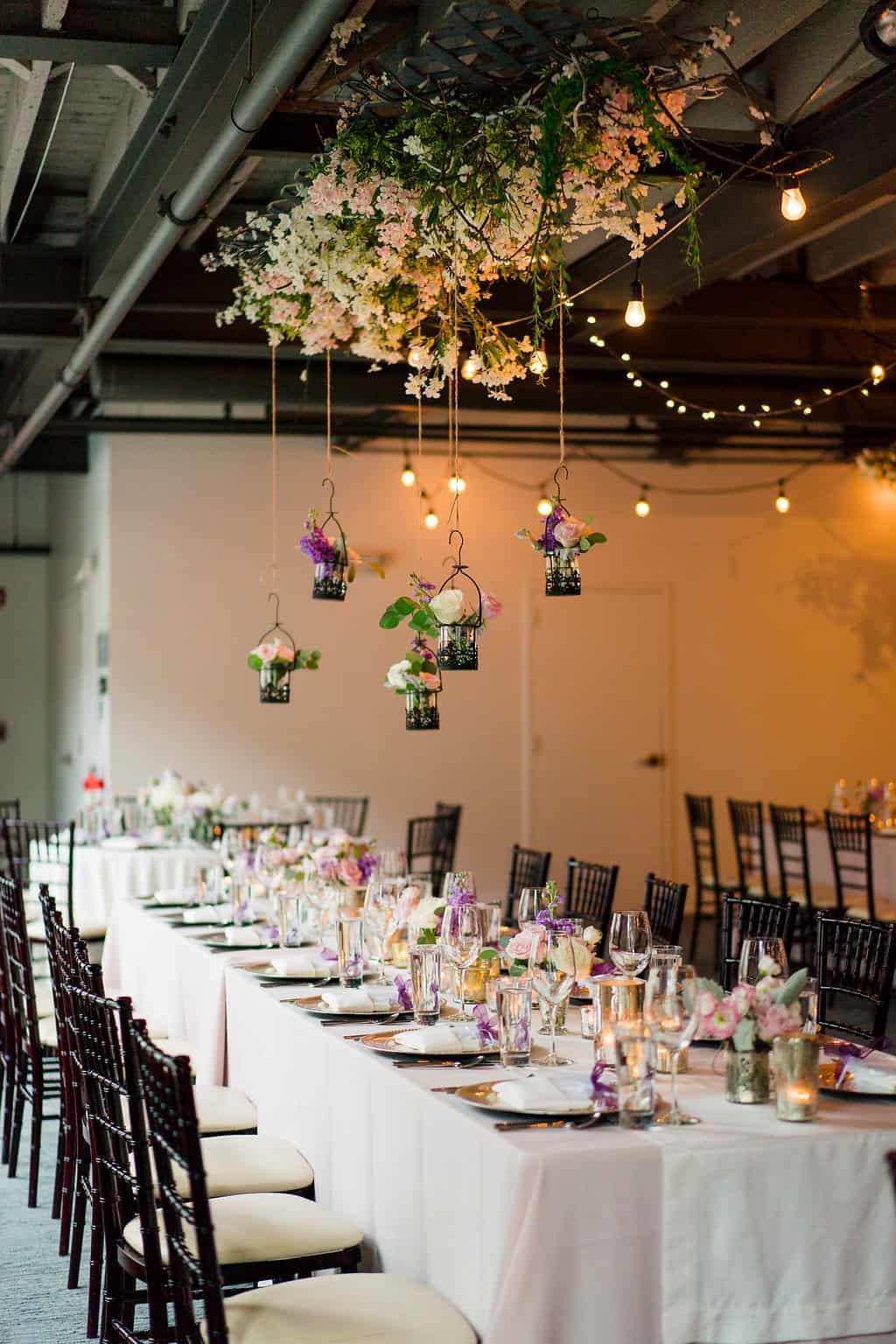 Beautiful wedding reception with floral centerpieces and hanging decorations.