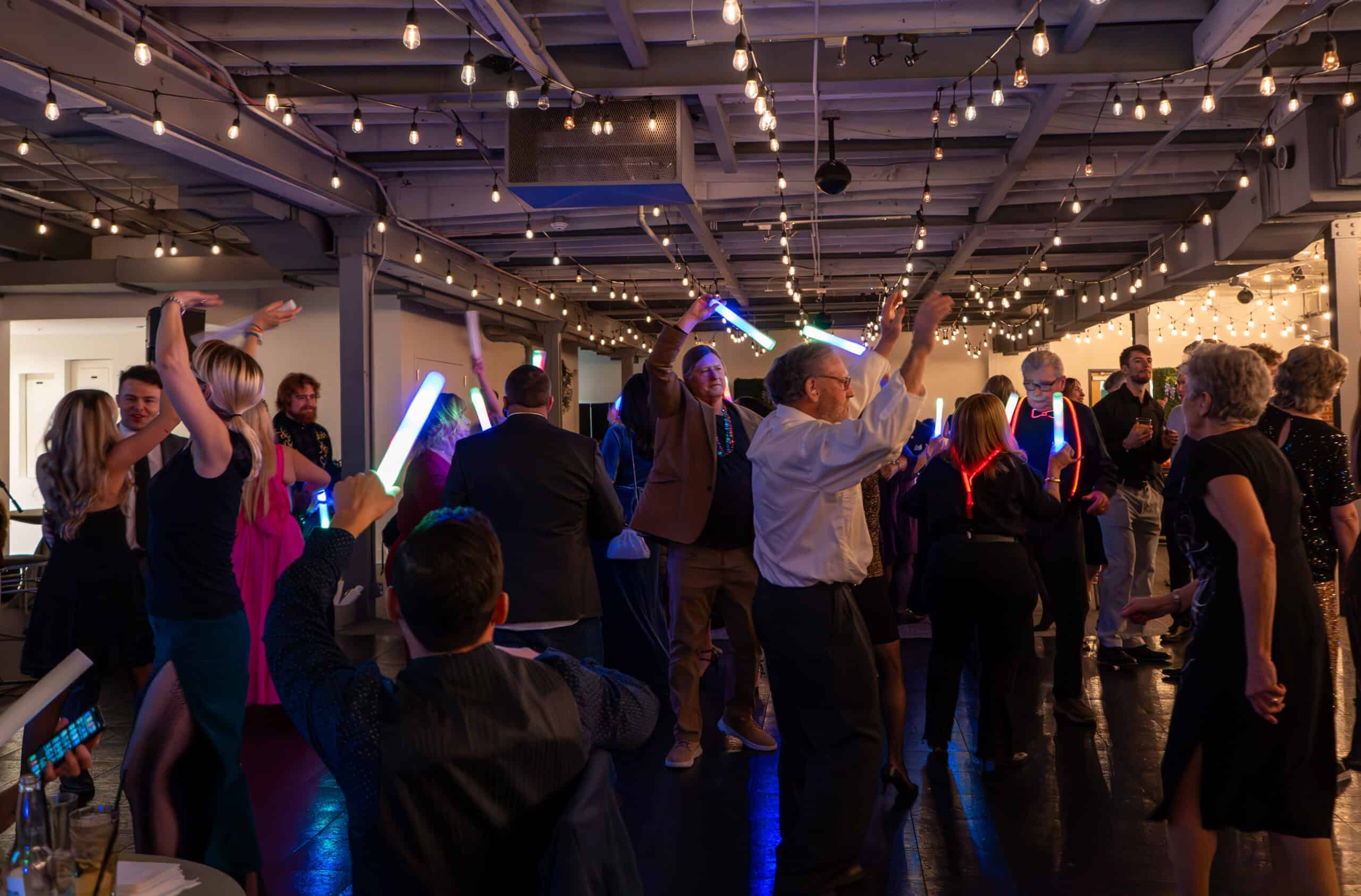 People dancing and celebrating at SKY Armory with colorful lights and glow sticks.