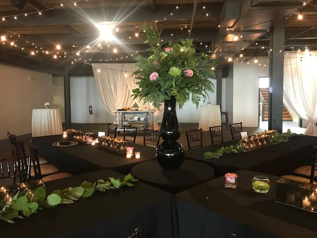 Beautifully decorated event space with floral centerpiece and string lights.