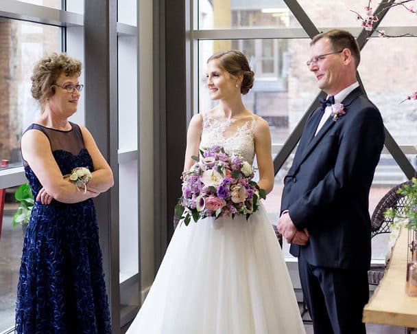 Bride and groom with officiant during wedding at SKY Armory.