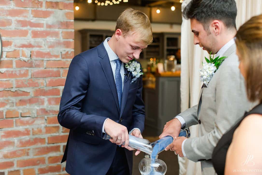 Groom pouring champagne at wedding reception with friends.