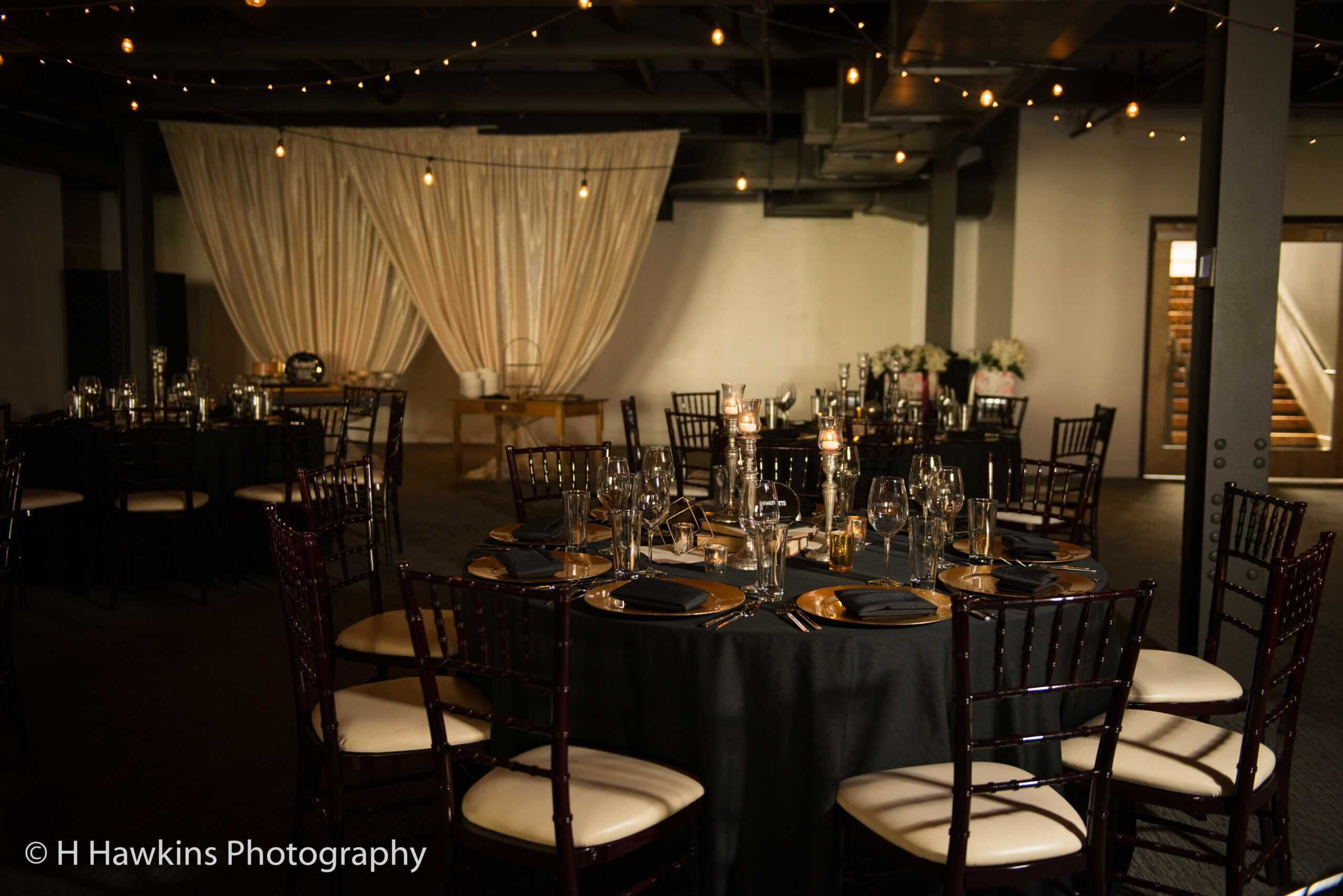 Event setup with round tables, black tablecloths, and elegant place settings at SKY Armory.