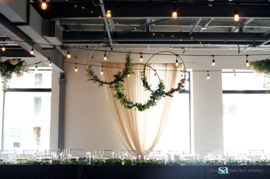 Elegant event decor with hanging floral hoops and string lights at Sky Armory.