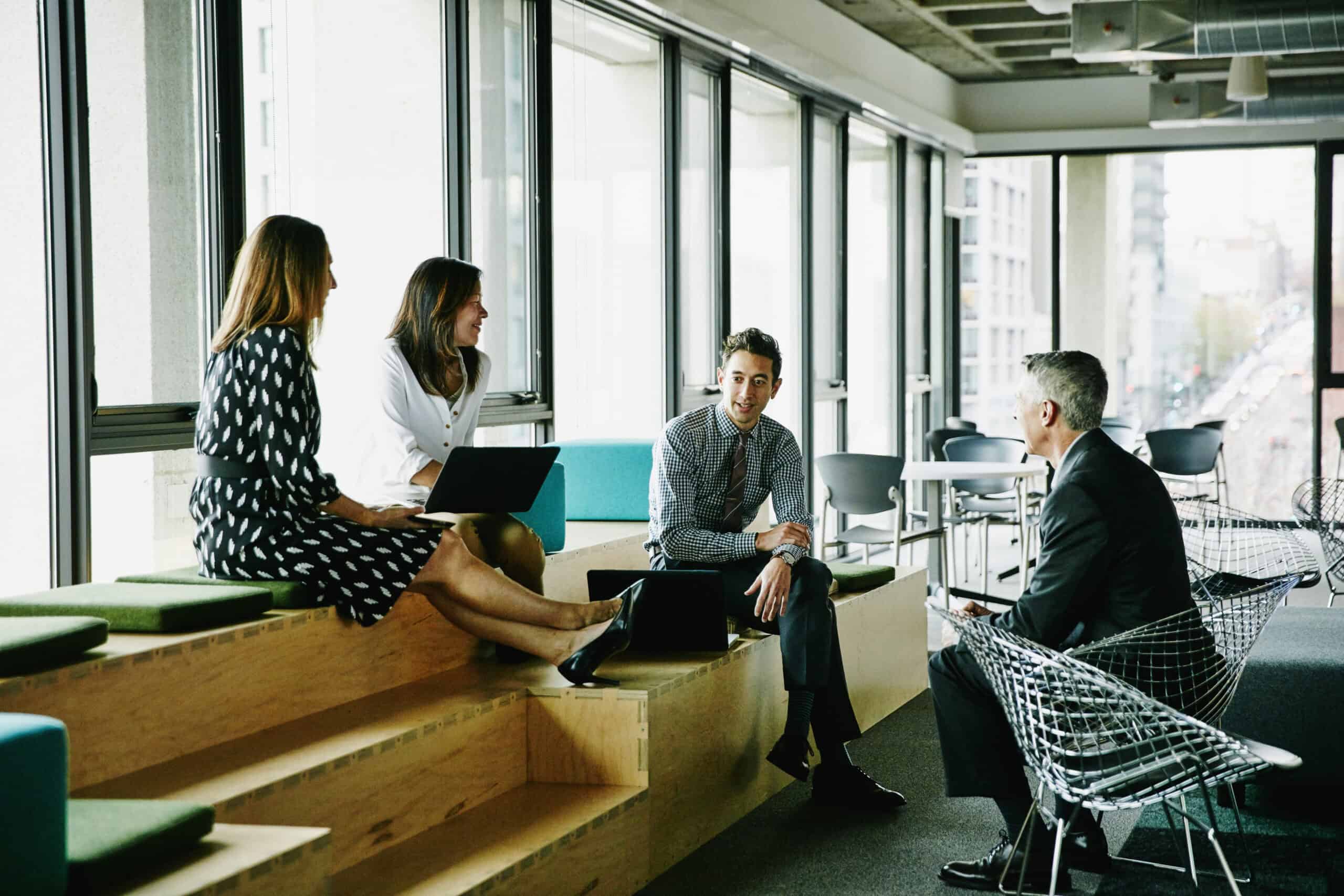 Business professionals having a meeting in a modern office space with large windows.