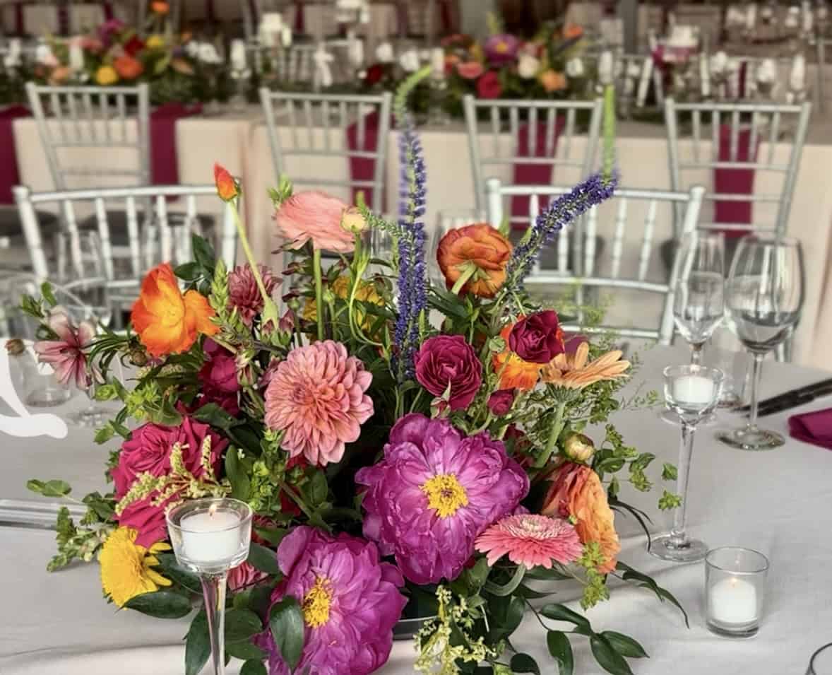 Colorful floral centerpiece with pink, orange, and purple flowers for wedding decor.