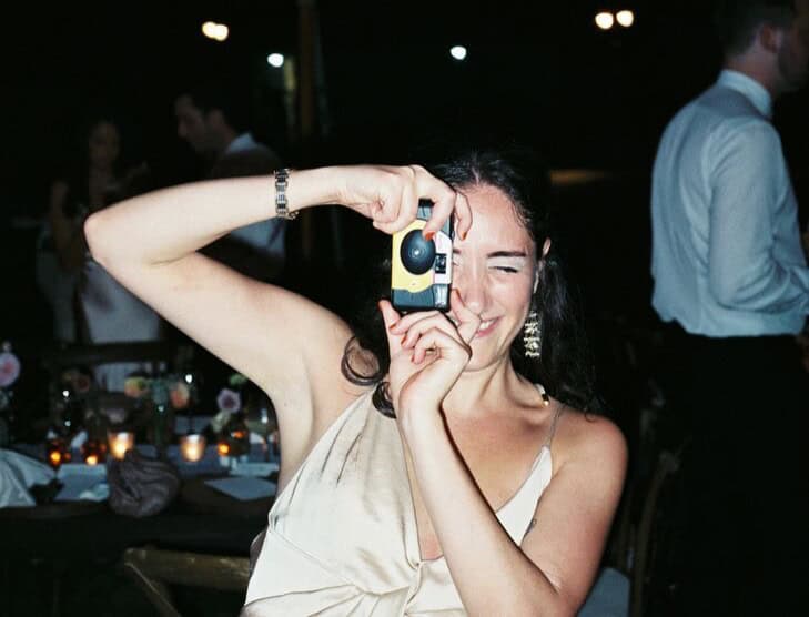Woman with camera capturing moment at wedding reception.
