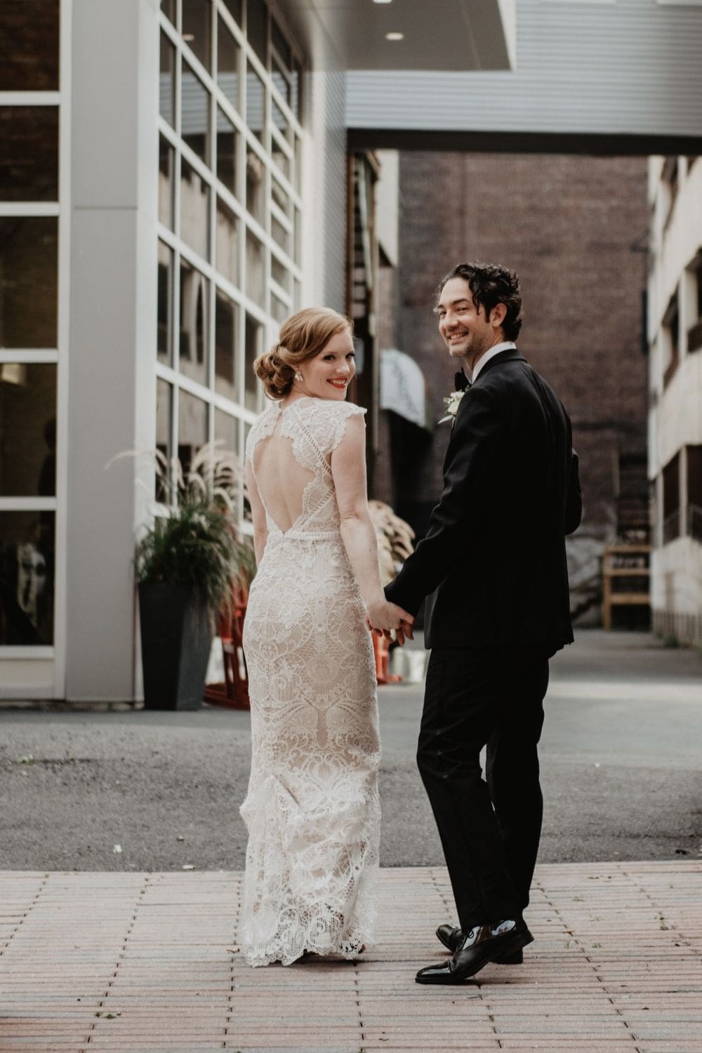 Stylish wedding couple holding hands in urban setting at SKY Armory.