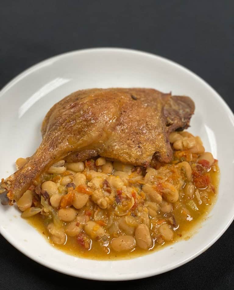Juicy roasted chicken served over hearty bean stew with vegetables.